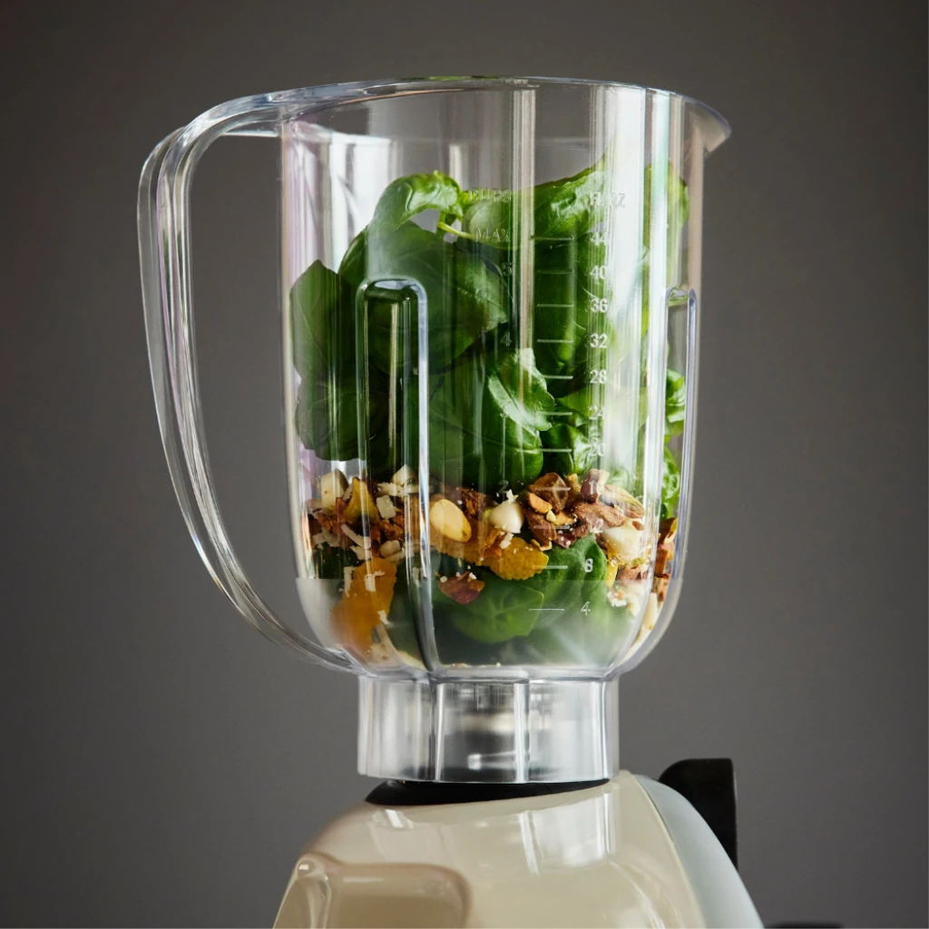 Close up of an Ankarsrum blender attachment filled with fresh salad and greens, demonstrating the versatility of this professional baking mixer machine.